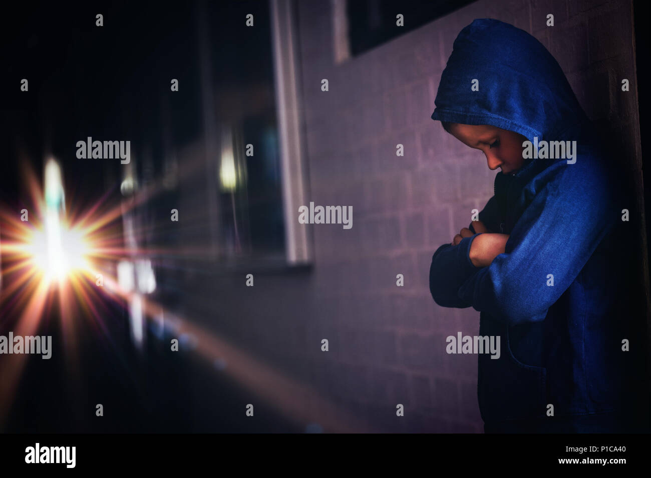 Boy standing alone by wall in corridor Stock Photo