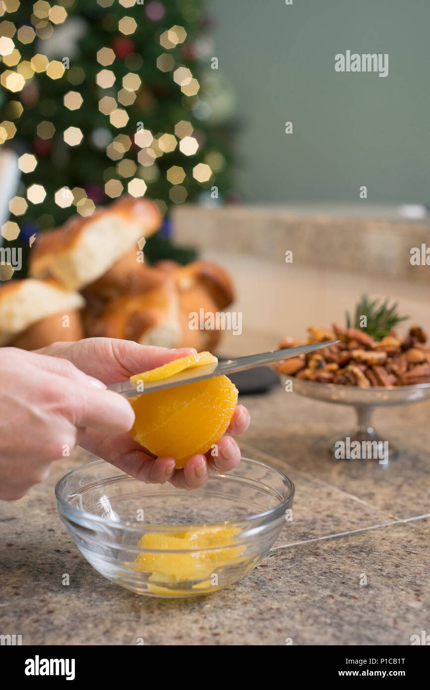 A woman preparing an orange to use for a citrus addition to a salad. Stock Photo