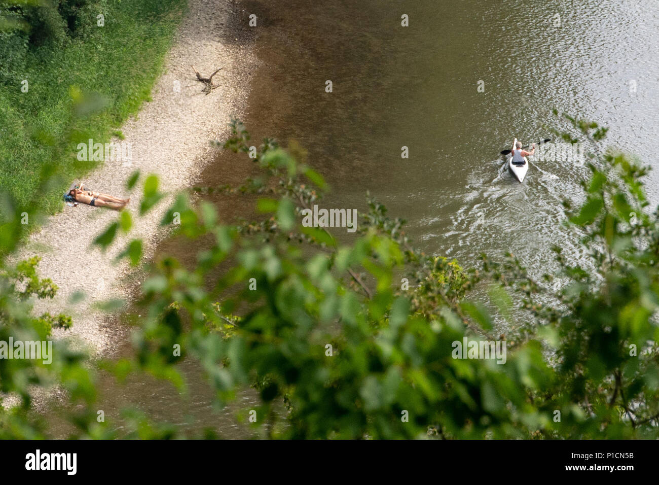 11 June 2018, Germany, Kelheim: An kayak driver drives past bathing guests at the Danube Gorge. Photo: Armin Weigel/dpa Stock Photo