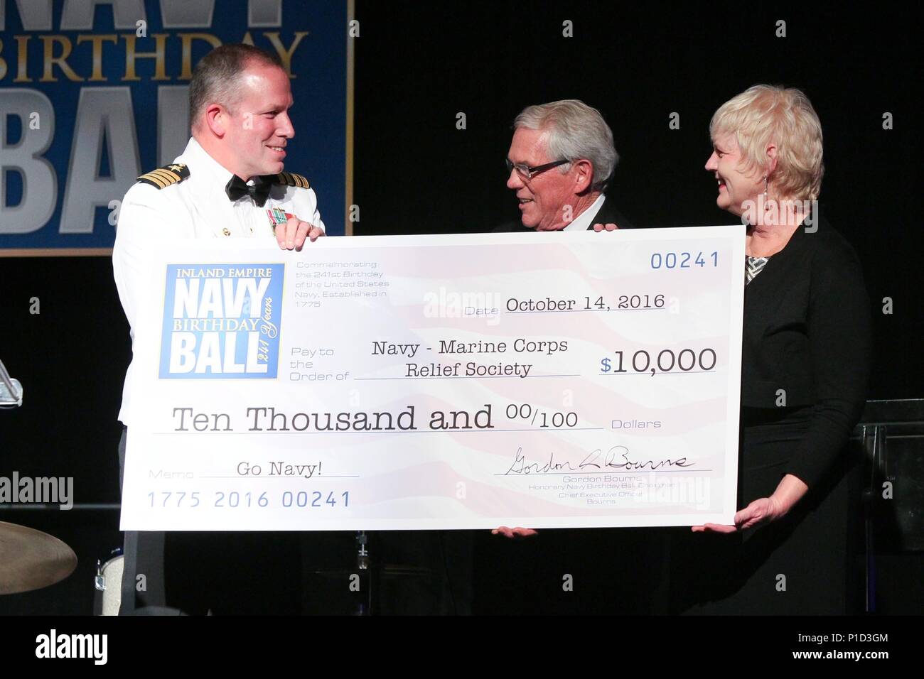 161014-N-HW977-441  RIVERSIDE, Calif. (Oct. 14, 2016) Capt. Stephen H. Murray, commanding officer of Naval Surface Warfare Center (NSWC), Corona Division, left, and Gordon Bourns, honorary Inland Empire Navy Birthday Ball chairman, present check to Donna Miranda, Navy-Marine Corps Relief Society (NMCRS) San Onofre and Camp Pendleton director. The sold-out event, commemorating the Navy's 241st birthday, included dinner, ceremonies, music, and dancing with all proceeds to benefit NMCRS. (U.S. Navy photo by Greg Vojtko/Released) Stock Photo