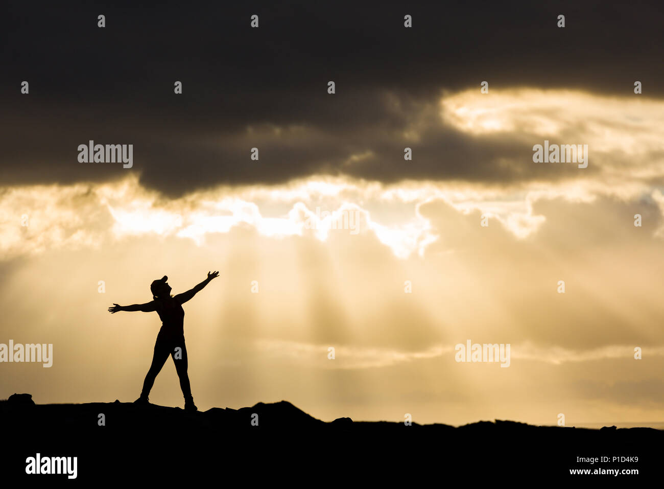 Woman enjoying the great outdoors looking toward the sky during a dramatic sunset. Stock Photo