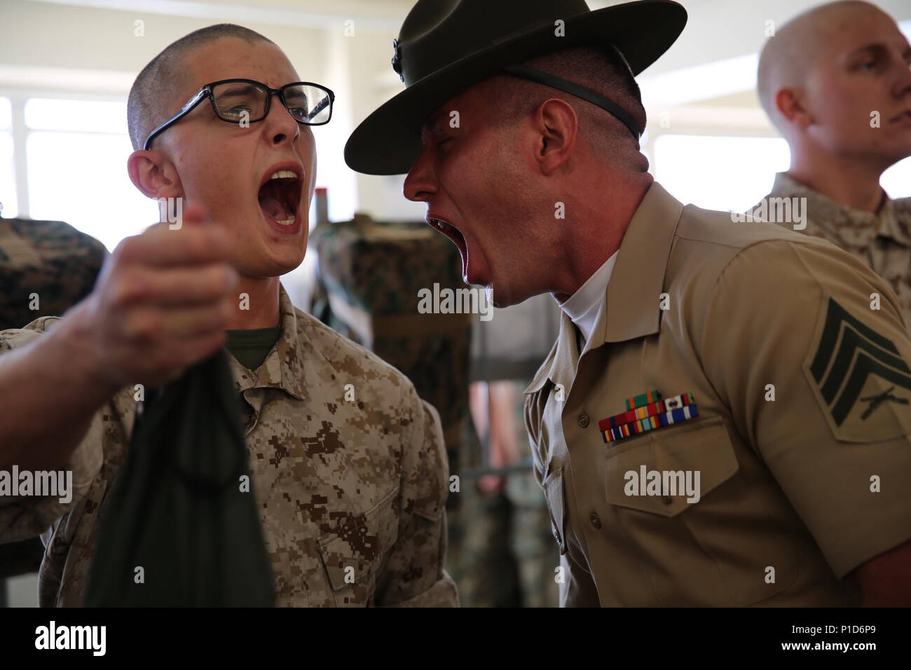 A drill instructor from Charlie Company, 1st Recruit Training Battalion, corrects a recruit during pick up at Marine Corps Recruit Depot San Diego, Oct. 14. In the first hours recruits are with their drill instructors, they learn the rules and regulations of recruit training, covering everything from how to act in the squad bay to how to speak to the drill instructors. Annually, more than 17,000 males recruited from the Western Recruiting Region are trained at MCRD San Diego. Charlie Company is scheduled to graduate Jan. 6. Stock Photo
