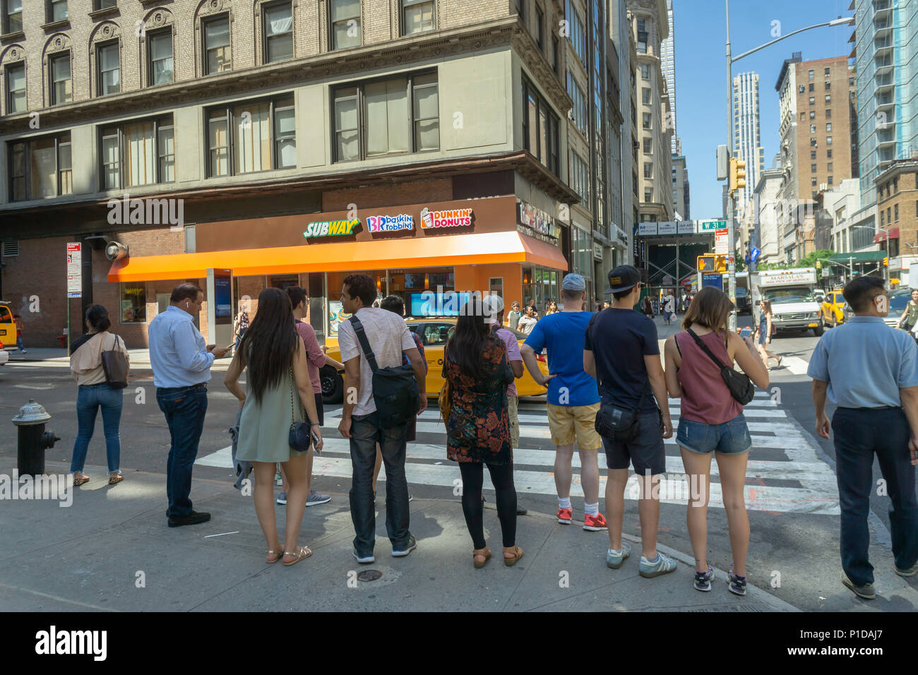 Pedestrians wait to cross in front of a triple-franchised storefront containing Subway sandwiches, Baskin-Robbins ice cream and Dunkin' Donuts franchises in New York on Tuesday, May 29, 2018. (Â© Richard B. Levine) Stock Photo