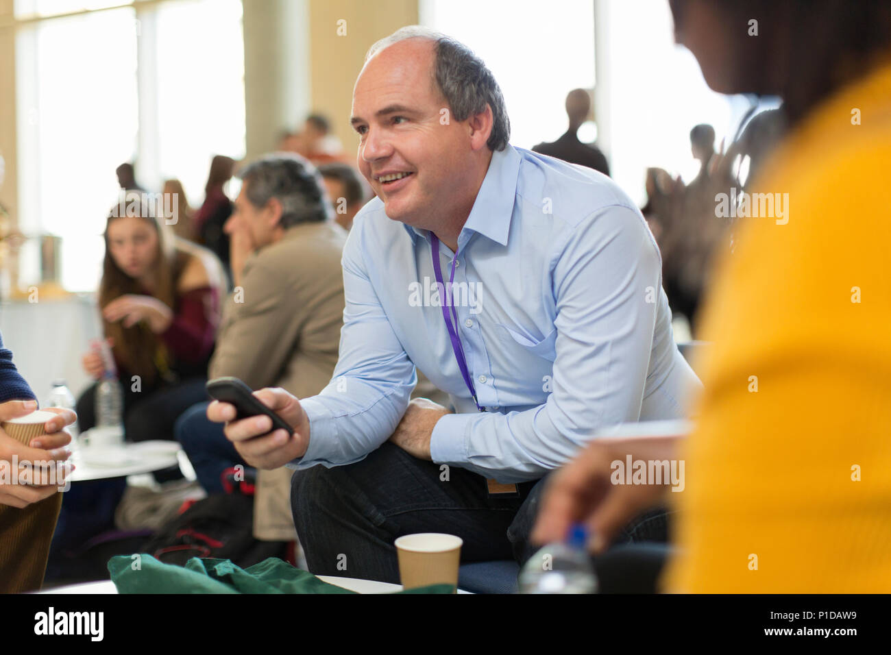 Smiling businessman using smart phone at conference Stock Photo