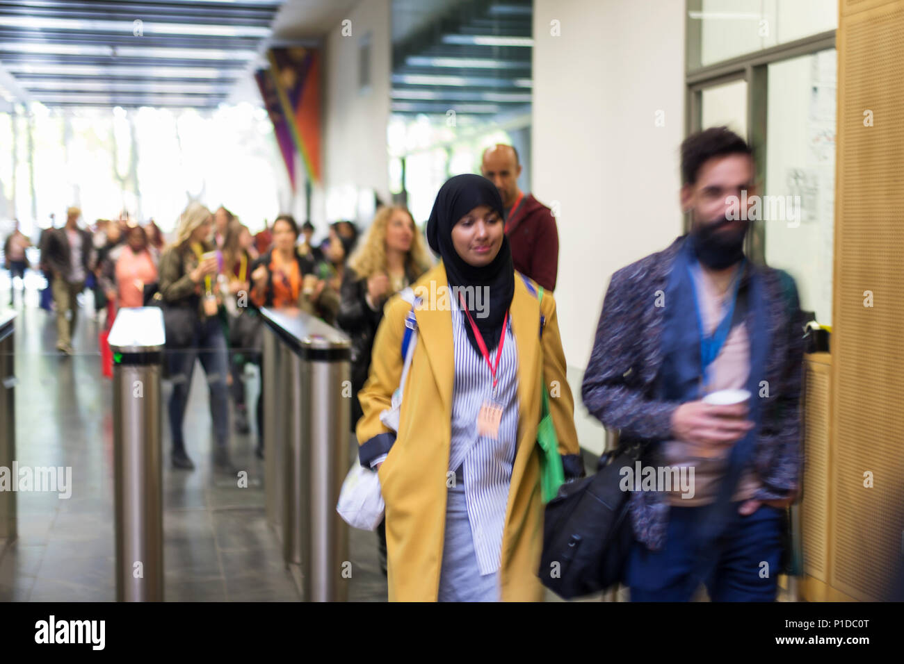 People arriving, entering turnstile at conference Stock Photo