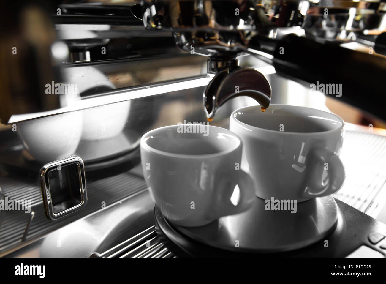 Italian espresso machine on a counter in a restaurant dispensing freshly brewed coffee into two small cups Stock Photo