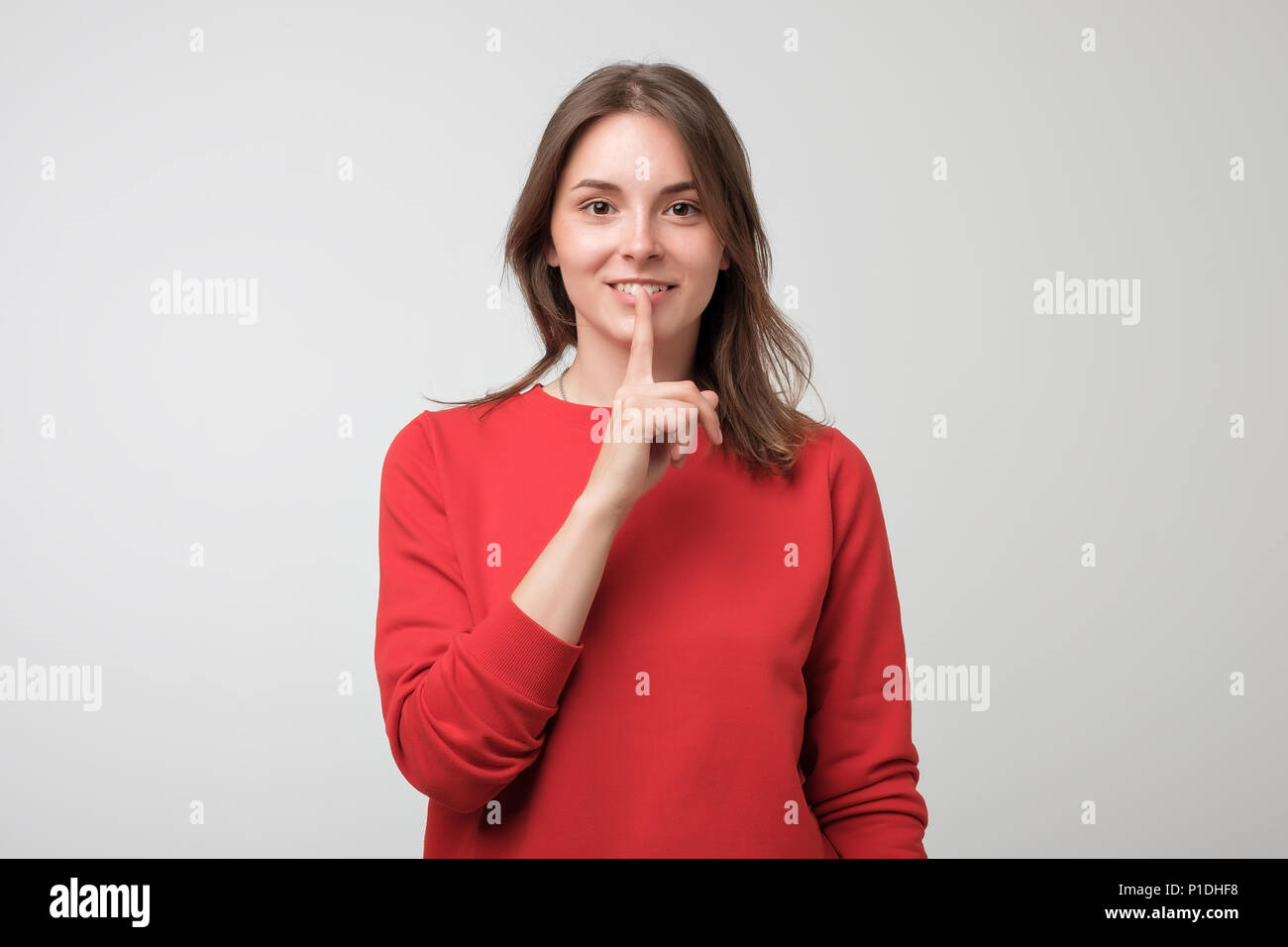 Beautiful european woman in red pulover showing silence sign Stock Photo