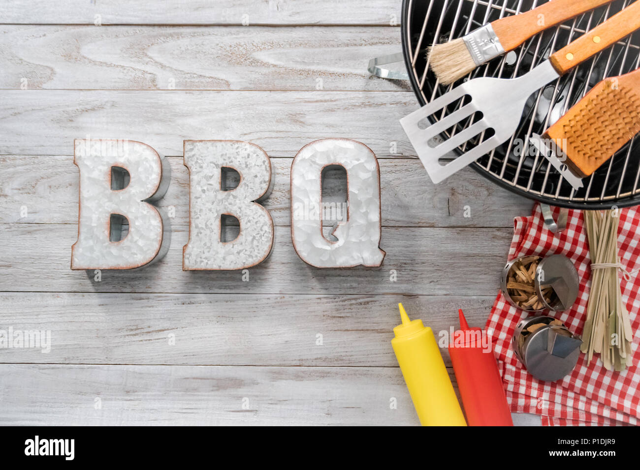 Metal BBQ sign with BBQ cooking tools on a wood background Stock Photo