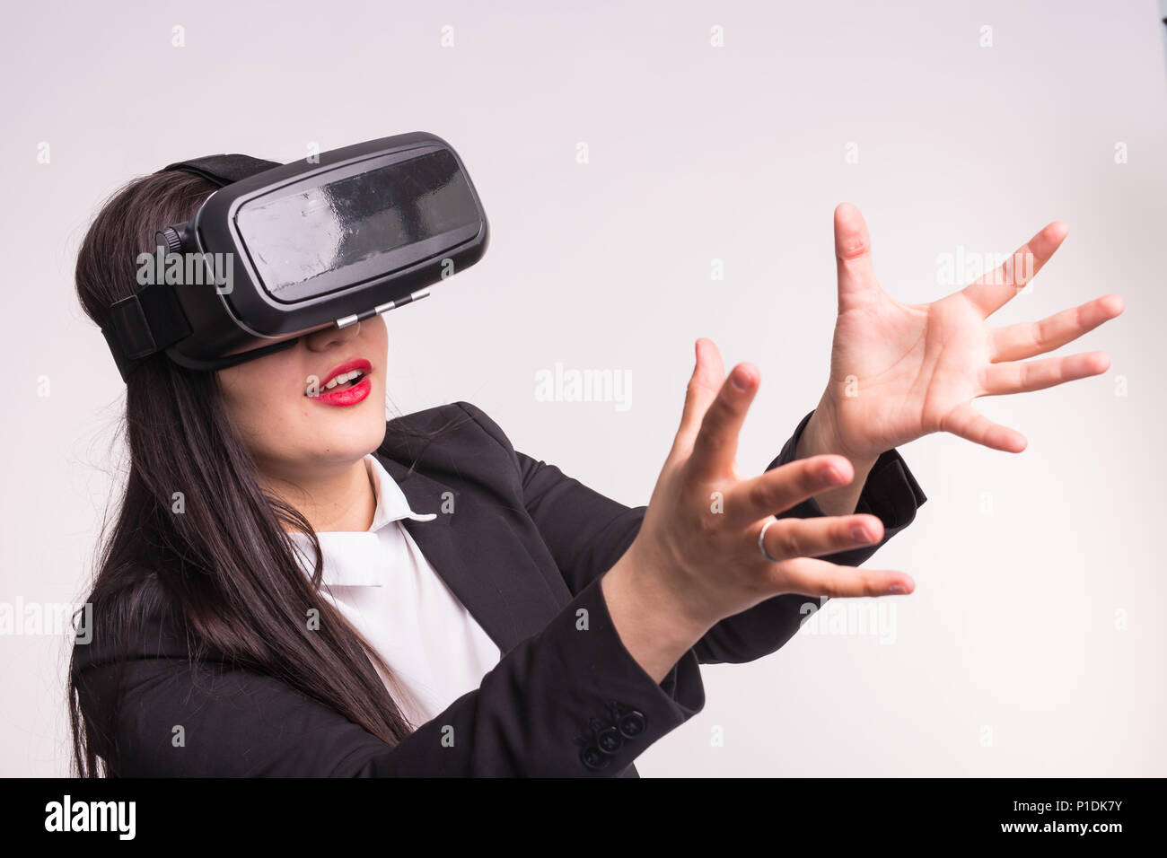 Happy excited young woman using a virtual reality headset on white ...