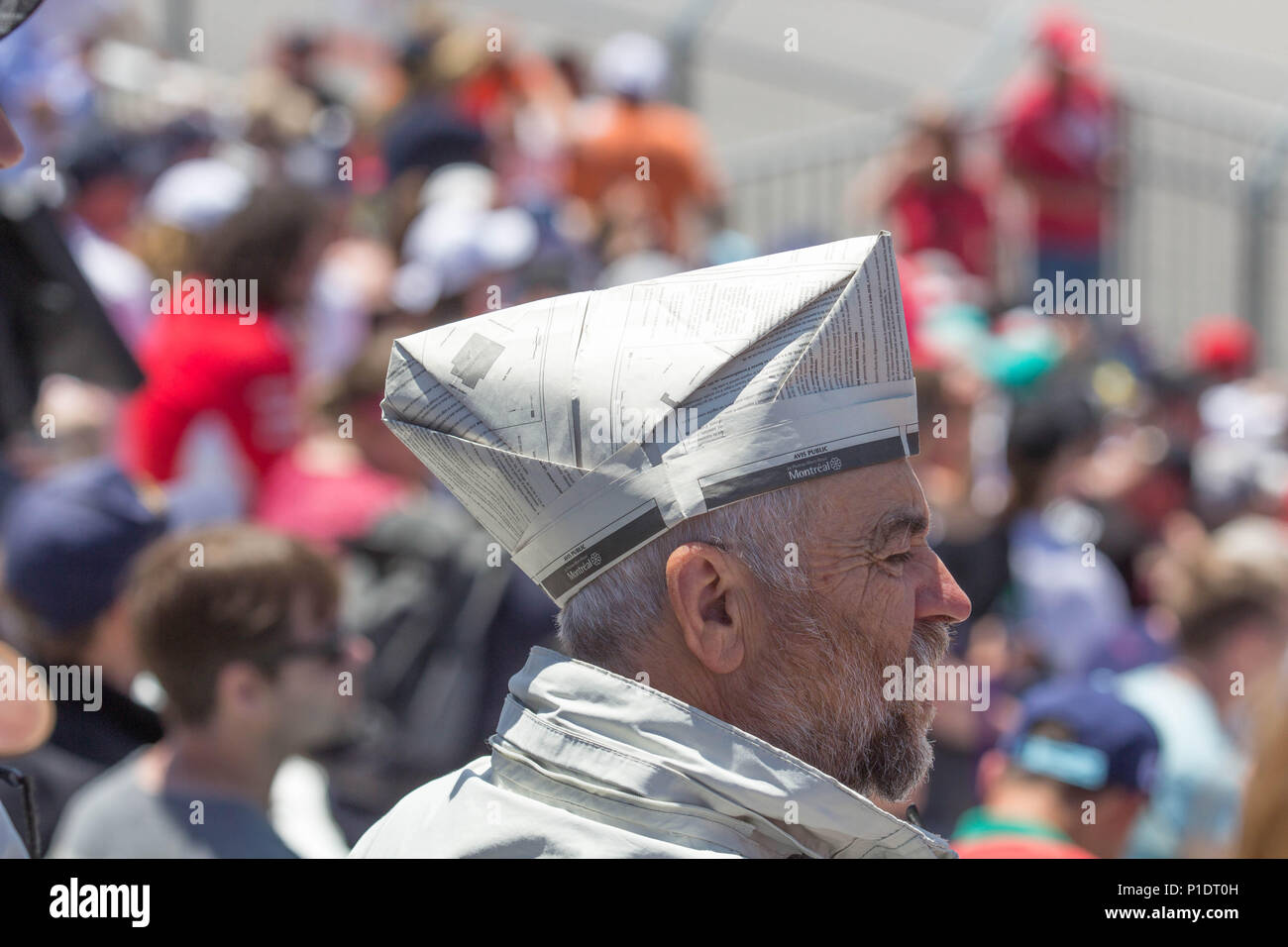 Old man in a crowd with a newspaper sailor hat Stock Photo Alamy