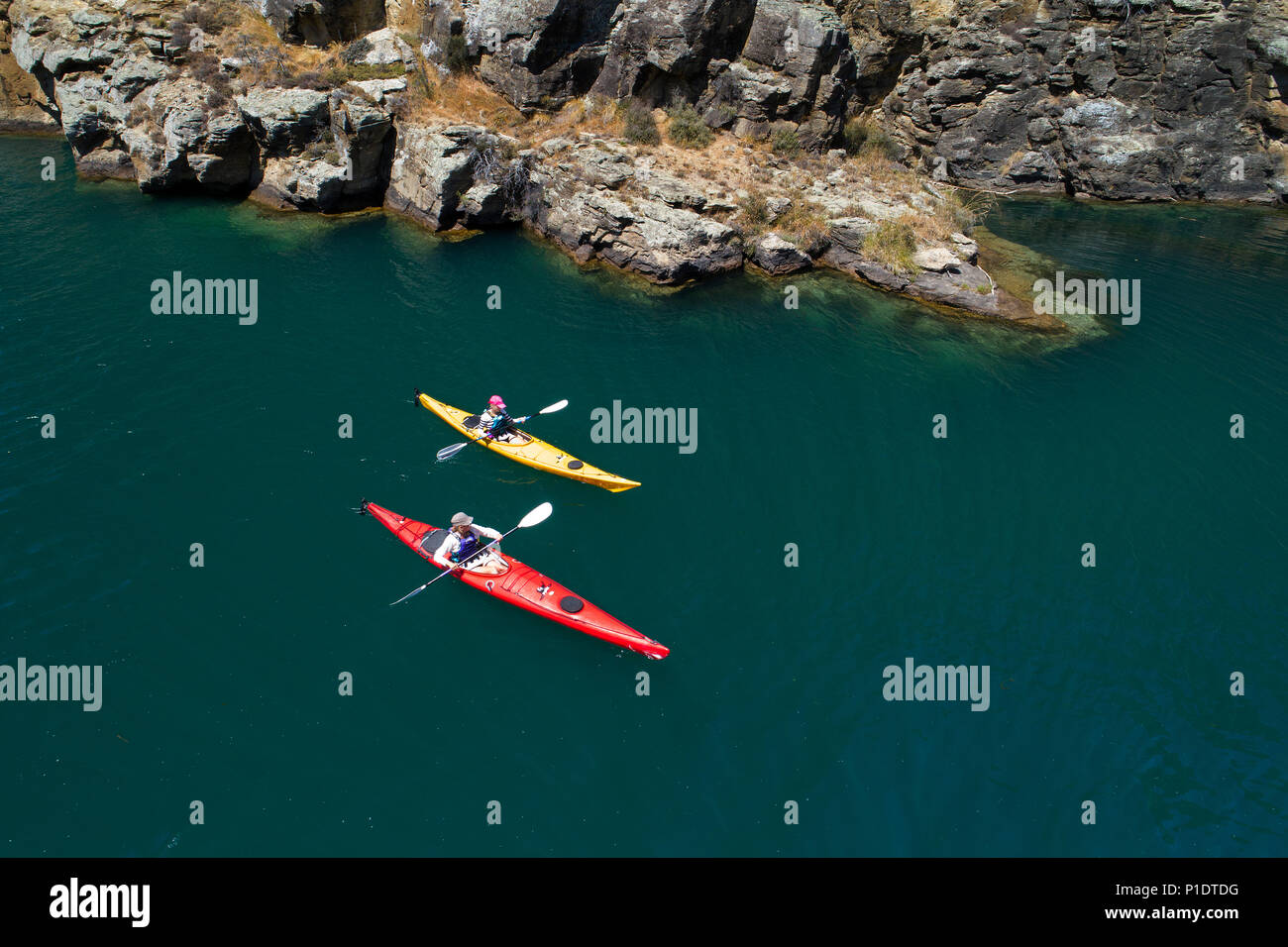 Kayakers and cliffs, Cromwell Gorge, Lake Dunstan, Central Otago, South Island, New Zealand - drone aerial Stock Photo