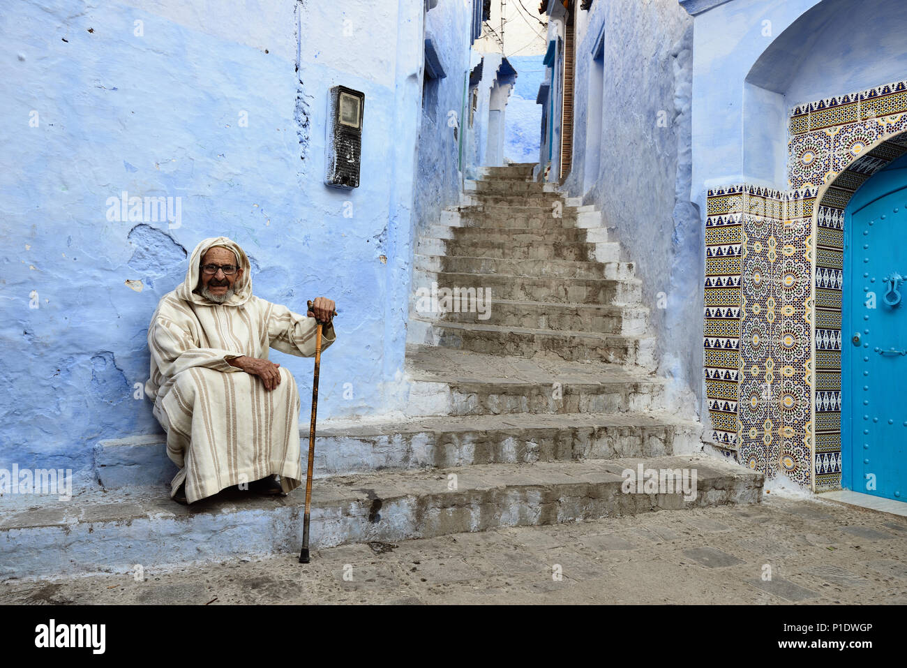 CHEFCHAOUEN, MOROCCO - 27 NOVEMBER 2015:  Older man sitting on the doorstep of the house in the blue city in Morocco Stock Photo