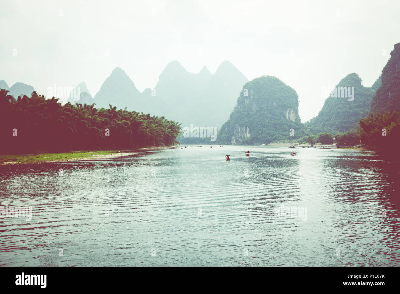 Scenic view of small tourist bamboo rafts sailing along the Li River among green woods and karst mountains at Yangshuo County of Guilin, China. Yangsh Stock Photo