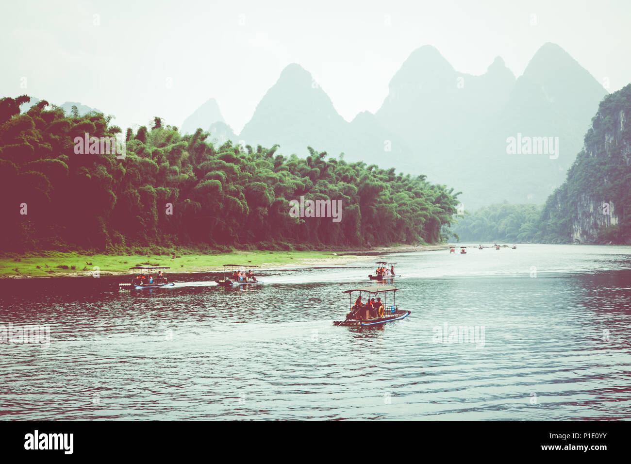 Scenic view of small tourist bamboo rafts sailing along the Li River among green woods and karst mountains at Yangshuo County of Guilin, China. Yangsh Stock Photo