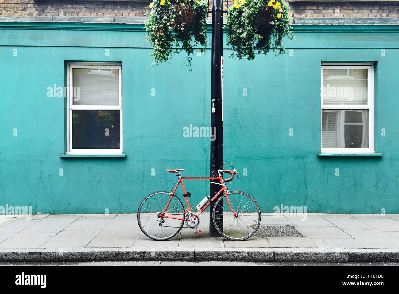 Orange racing bicycle against a teal  turquoise wall Stock Photo