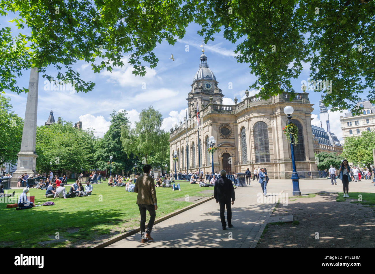 The grounds around St Philip's Cathedral in the centre of Birmingham, UK with people sitting on the grass in the sunshine Stock Photo