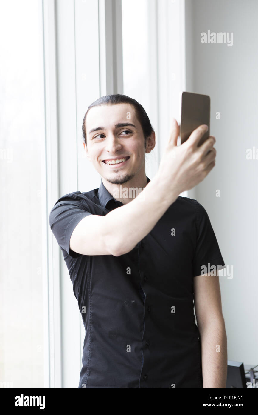 A young businessman taking a picture with a cellphone in a modern office. Stock Photo