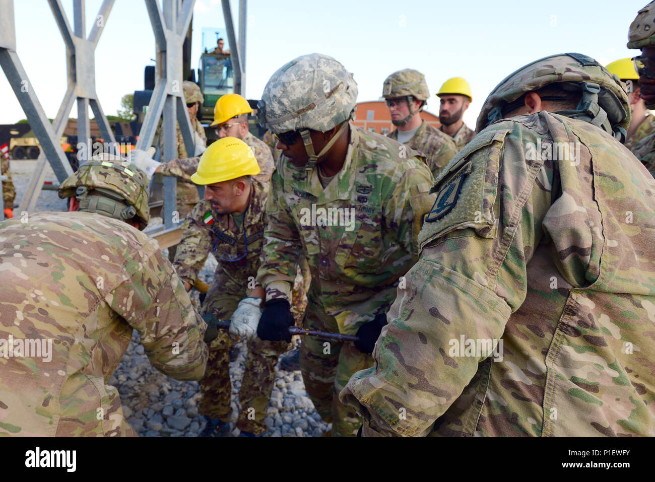 U.S. Army paratroopers assigned to the 173rd Airborne Brigade, 54th Brigade Engineer Battalion and Italian army soldiers from the 2nd Engineer Regiment Pointieri Piacenza, work together to assemble the pieces of the bridge during the Exercise Livorno Shock in Leghorn Army  DEPOT, Italy, Oct. 22, 2016. Livorno Shock is a combined readiness exercise designed to familiarize U.S. paratroopers with river crossing capabilities and is led by the Italian Army’s 2nd Engineer Regiment Pointieri. The 173rd Airborne Brigade is the U.S. Army's Contingency Response Force in Europe, providing rapidly-deployi Stock Photo