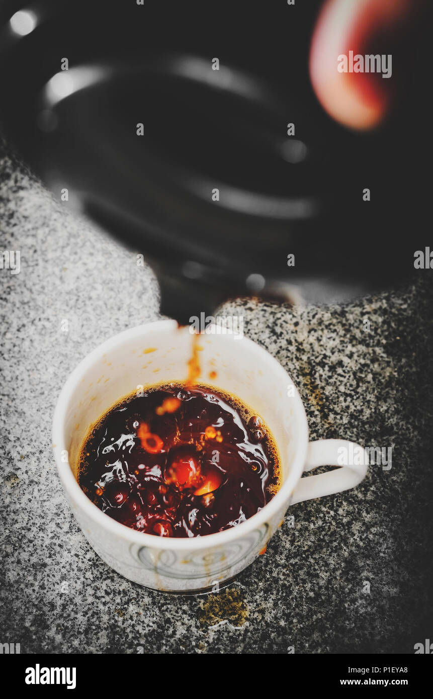 Pouring black coffee not gently into the cup. Pouring coffee from the thermos bottle with no