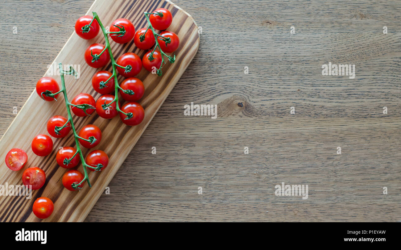 A branch of cherry tomatoes on wooden cutting board. selective focus ...