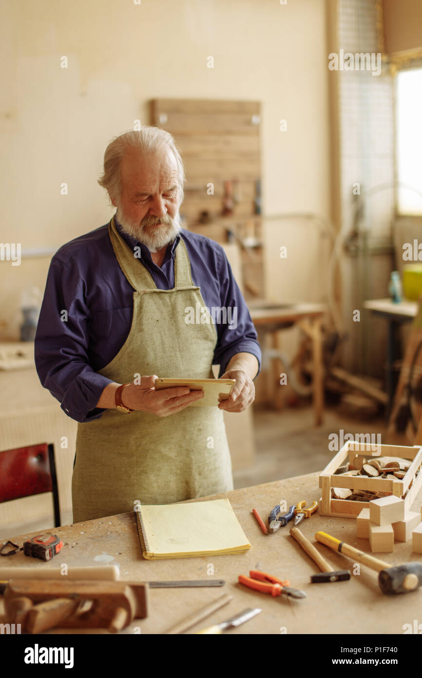 close up portrait of old carpenter using his tablet computer Stock Photo