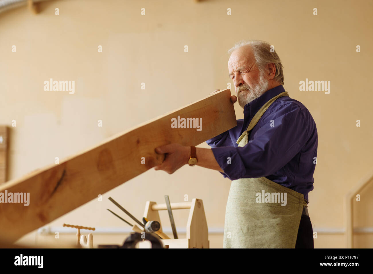 old craftsperson is working with timber indoors Stock Photo
