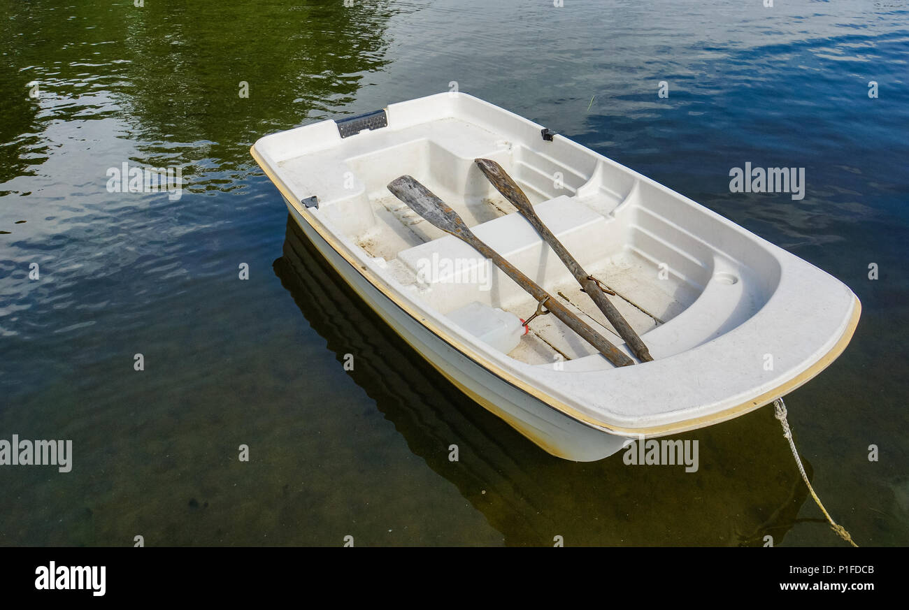 white row boat with two old wooden oars  moored on lake Stock Photo