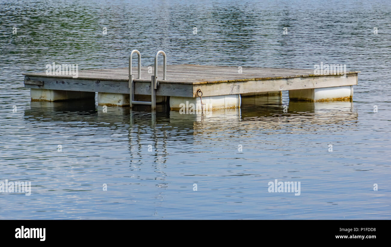 wooden swim raft with ladder floating on a lake Stock Photo