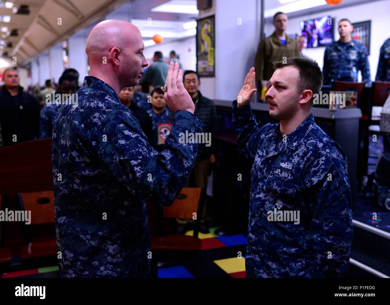 161028-N-OK605-007 MISAWA, Japan (Oct. 28, 2016) Petty Officer 2nd Class Christopher Plowden, from Stow, Maine, recites the oath of enlistment with Chief Warrant Officer 2 William Behr as he reenlists in the United States Navy. (U.S. Navy Photo by Petty Officer 2nd Class Samuel Weldin/Released) Stock Photo