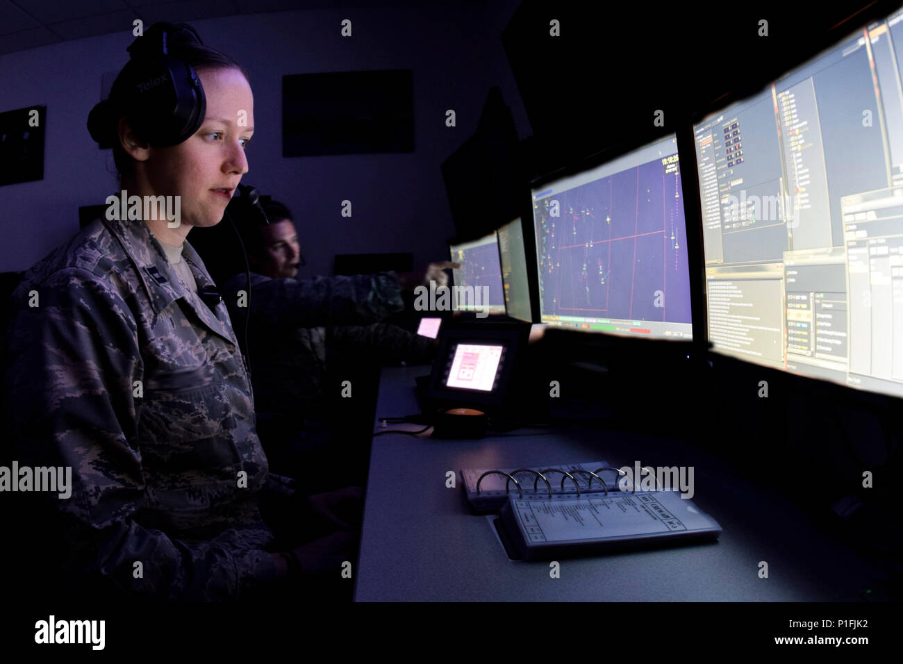 The faces of Capt. Jennifer and Maj. Michael, (last names not used in accordance with 12th Air Force directives) 752nd Operation Support Squadron air battle managers, are illuminated by the glow of their computer screens as they follow and point out target aircraft during a training scenario on the AN/TYQ-23A emulator Oct. 31, 2016, Tinker Air Force Base, Okla. Trainees in the ABM IQT course are working as part of a larger crew to test the communication and decision-making skills of the individuals and team under a stressful environment. (U.S. Air Force photo/Greg L. Davis) (Photo taken of sys Stock Photo