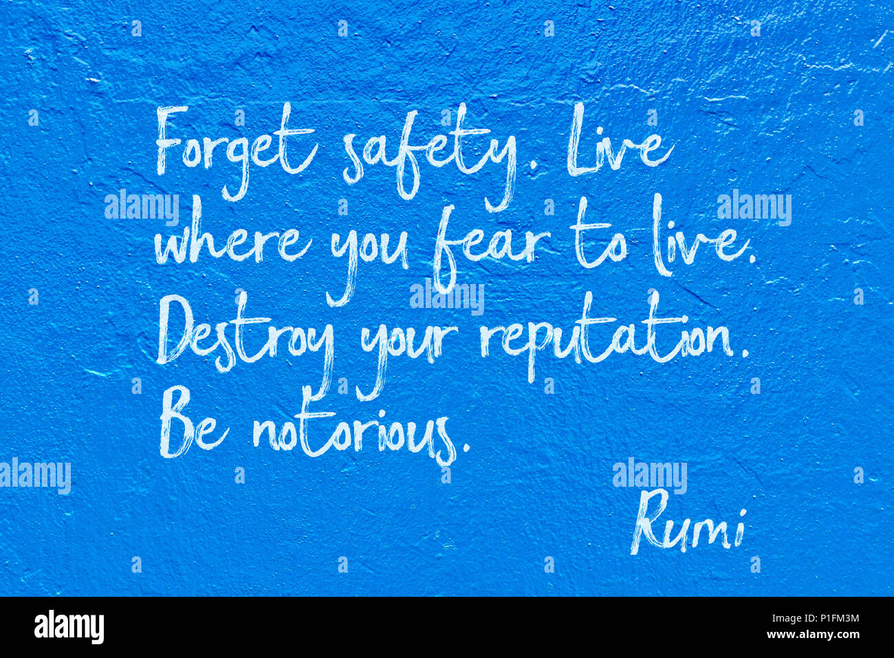 Destroy your reputation. Be notorious - ancient Persian poet and philosopher Rumi quote handwritten on blue wall Stock Photo