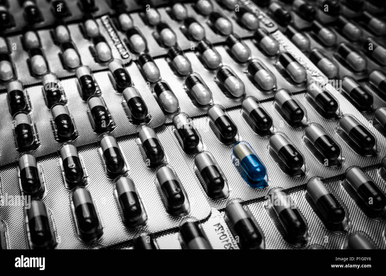 Antibiotics drug resistance. Bluewhite capsule pill standing out from crowd of blackwhite