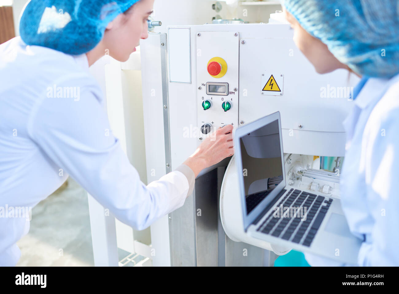 Two  Young Women Setting Machines at Food Factory Stock Photo