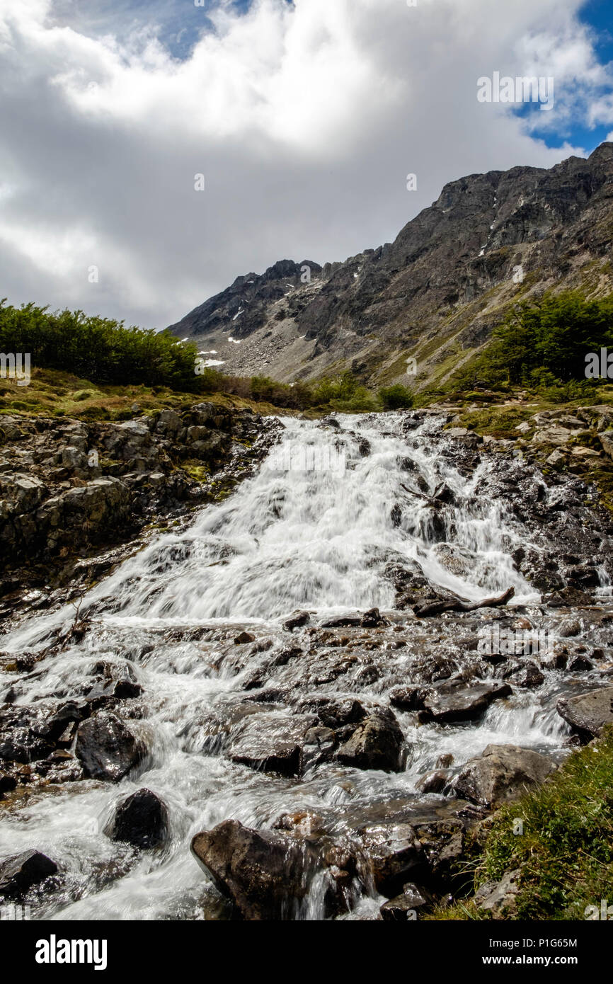 A narrow stream descends the mountain slopes near Laguna de los Témpanos, Ushuaia. It is one of the stunning views when hiking to this lagoon. Stock Photo