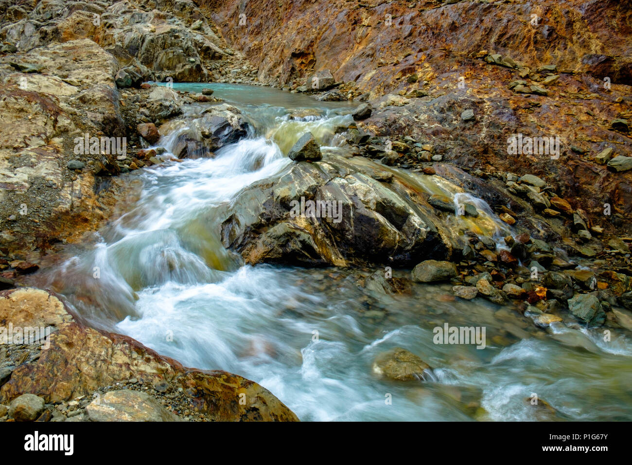 Glacial meltwater descends in between stunning, colorful rocks towards the 'Laguna de los Témpanos' near Ushuaia. It looks like a Martian landscape. Stock Photo