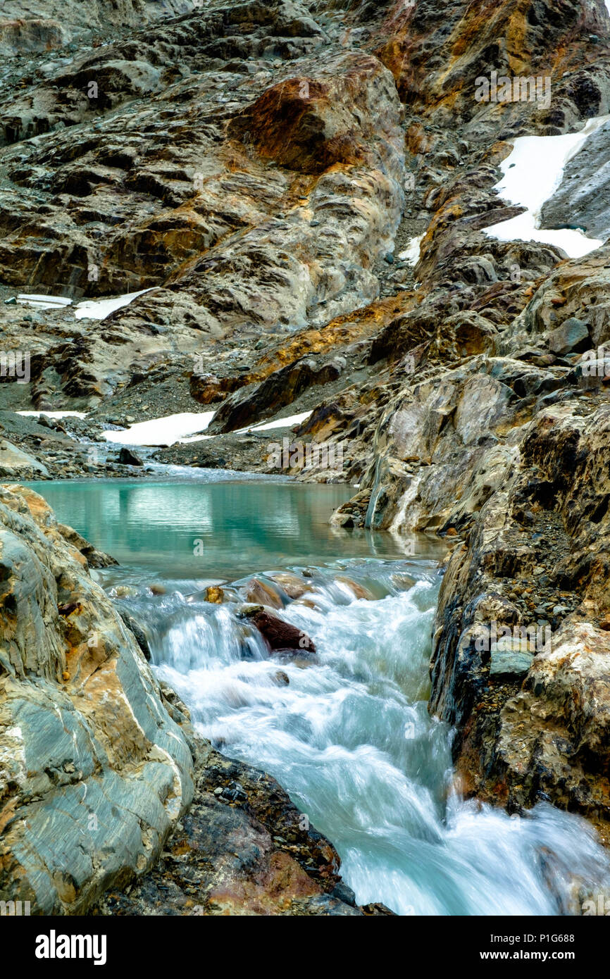 A narrow stream of water descends fast from a pond that exists of glacial meltwater. It is the reward of walking behind 'Laguna de los Témpanos'. Stock Photo