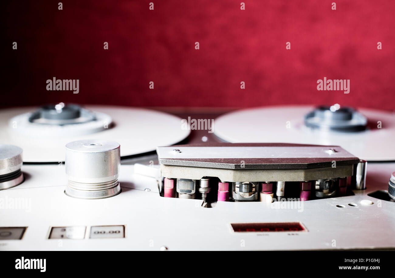 Macro close up of vintage professional analog multitrack one inch studio tape recorder, spool and head red background Stock Photo