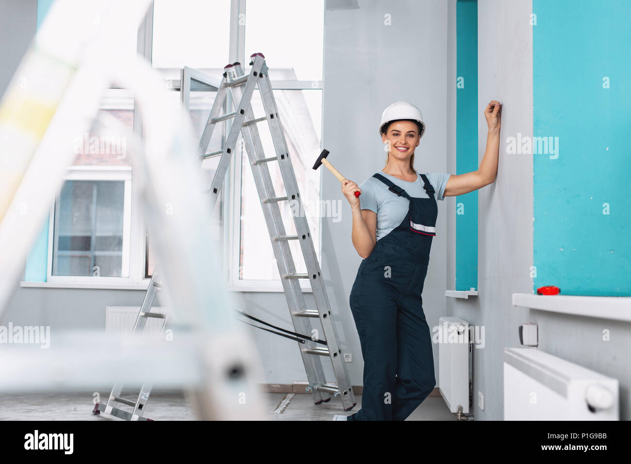 Cheerful female builder holding a hammer Stock Photo