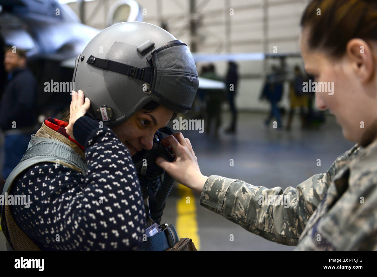 U.S. Air Force Staff Sgt. Skye Perry, a 354th Operations Support Squadron aircrew flight equipment craftsman, helps Kim Barrante, a screenwriter, try on a pilot’s helmet during a Civic Leader Tour, Oct. 25, 2016, at Eielson Air Force Base, Alaska. As part of the tour, civic leaders had the opportunity to meet pilots, observe static displays and try on flight crew equipment. (U.S. Air Force photo by Airman Eric M. Fisher) Stock Photo
