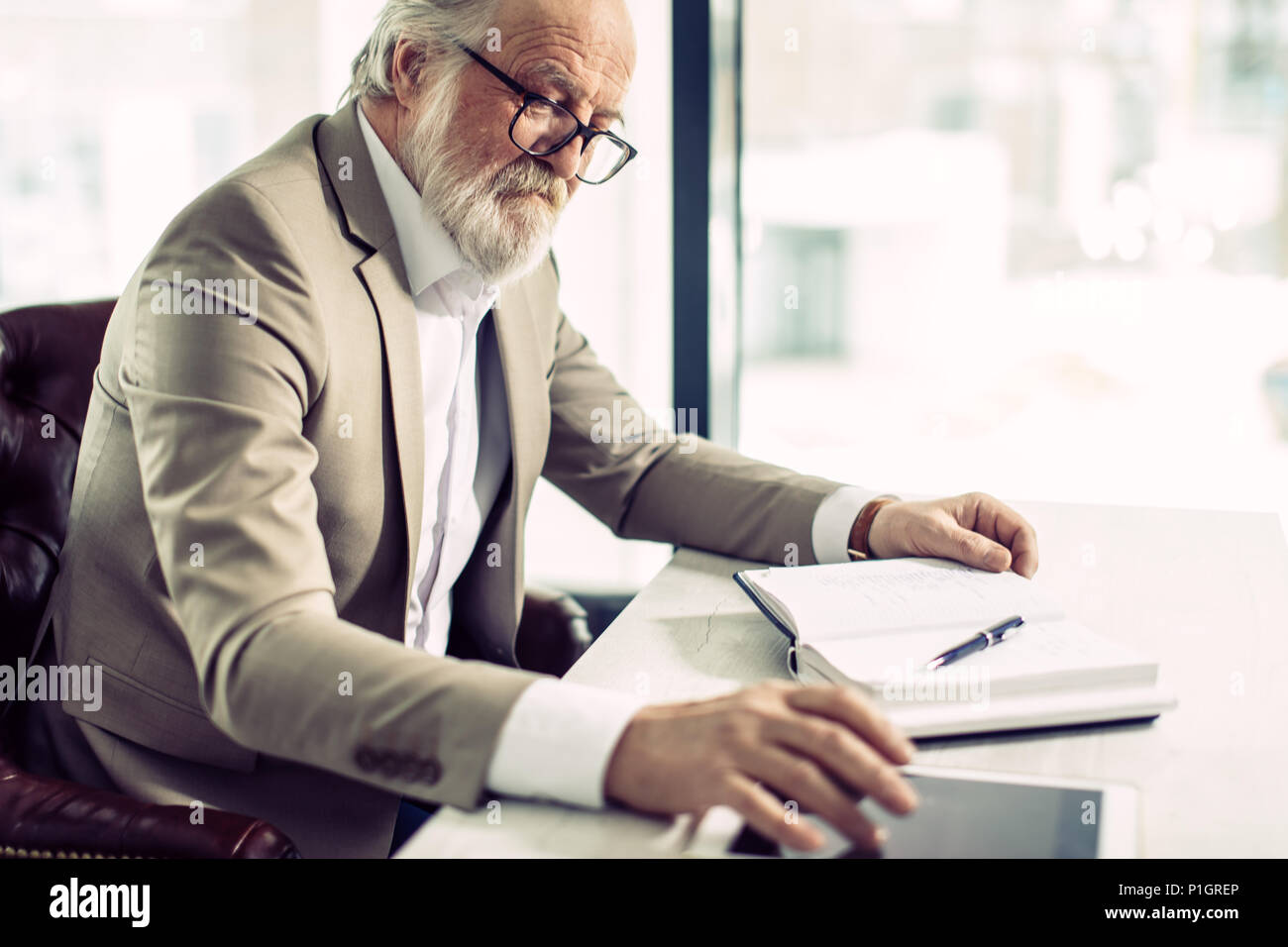 close up side view shot of senior chief sitting at work and using the ...