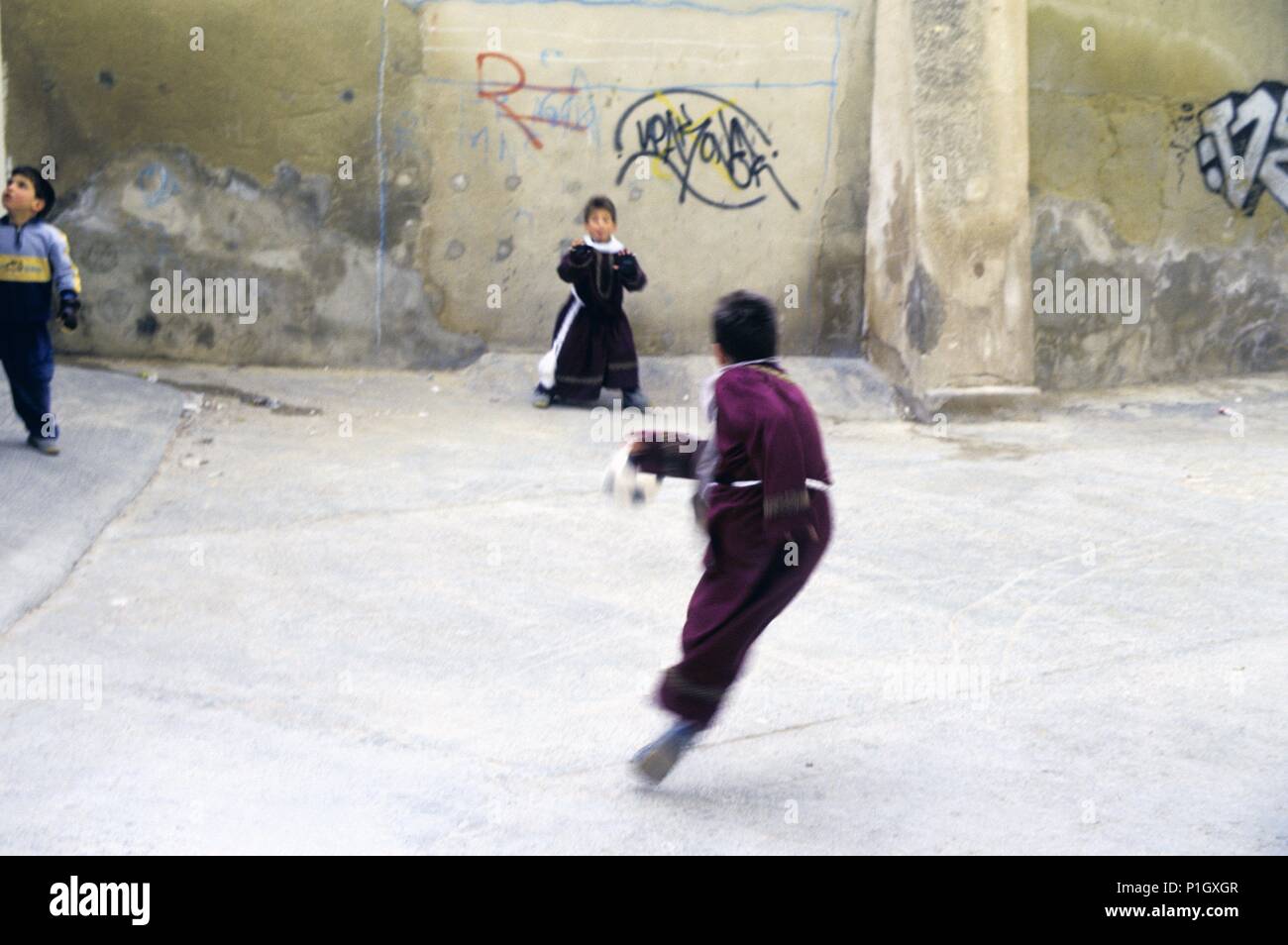 Hellín; children with religious dressing playing football during Holy Week / Semana Santa. Stock Photo