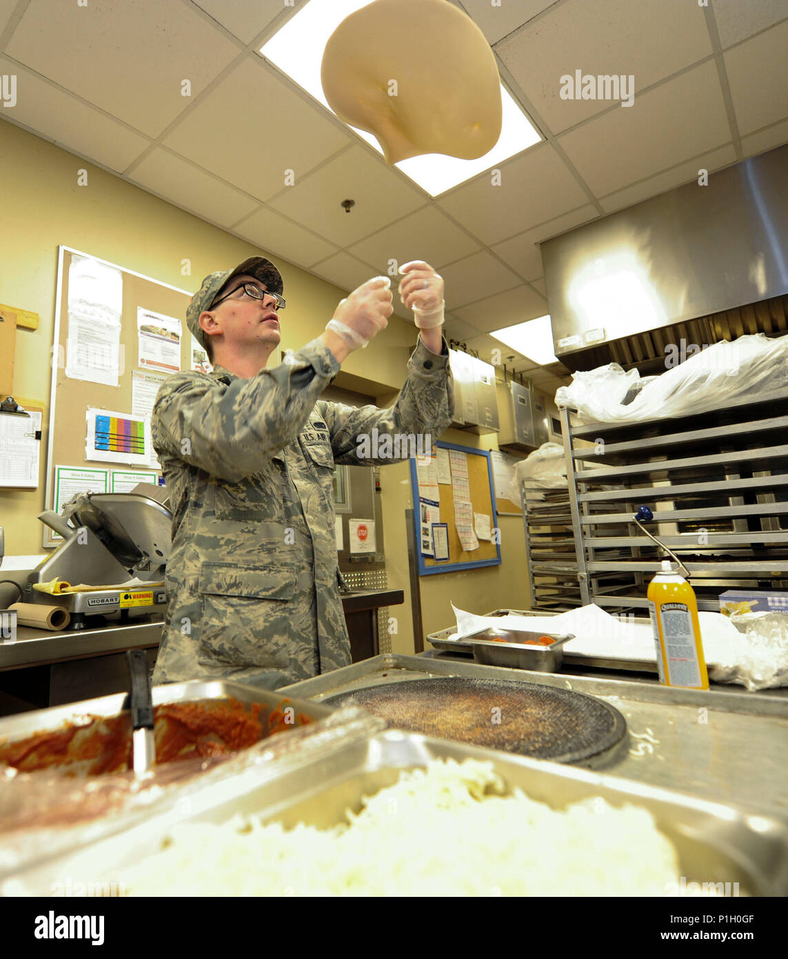 Senior Airman Boyd Cox, a food service journeyman assigned to the 28th Force Support Squadron tosses pizza dough in the air to prepare for the lunch rush at Ellsworth Air Force Base, S.D., Oct. 6, 2016. The Raider Café, Ellsworth’s dining facility, was recently nominated for the coveted John L. Hennessy award at the major command level, and will soon compete at the Air Force level within the next month. Stock Photo