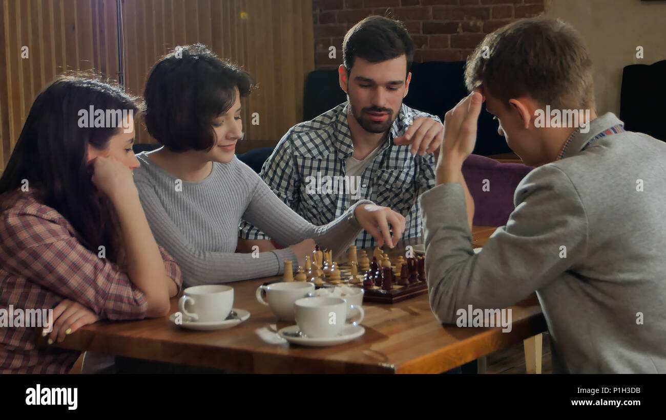 Young couple playing chess indoor with friends Stock Photo - Alamy