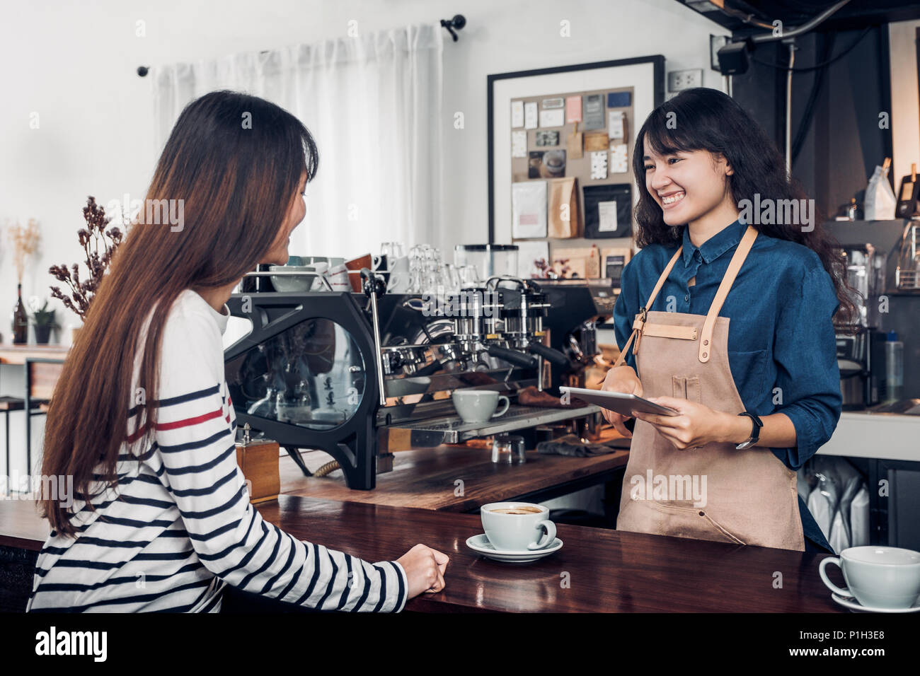 Asia Barista waiter take order from customer in coffee shop,cafe owner writing drink order at counter bar,Food and drink business concept,Service mind Stock Photo