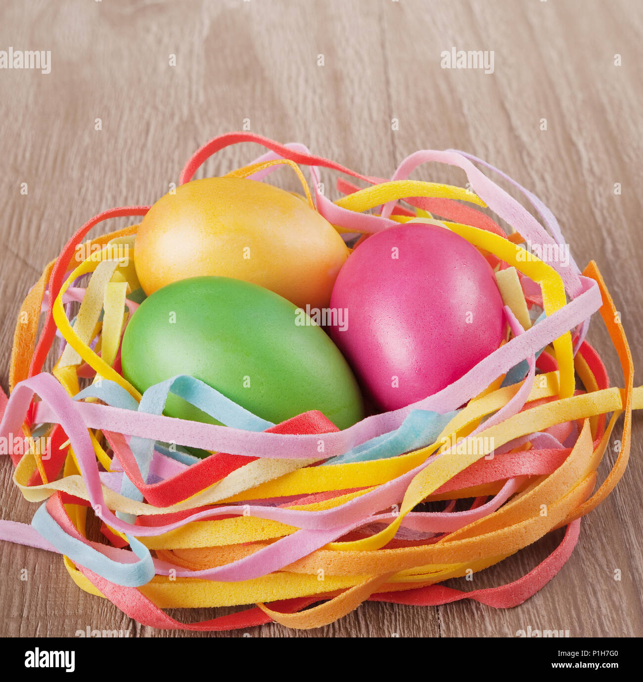 multicolored easter eggs  in the nest on old wooden table Stock Photo