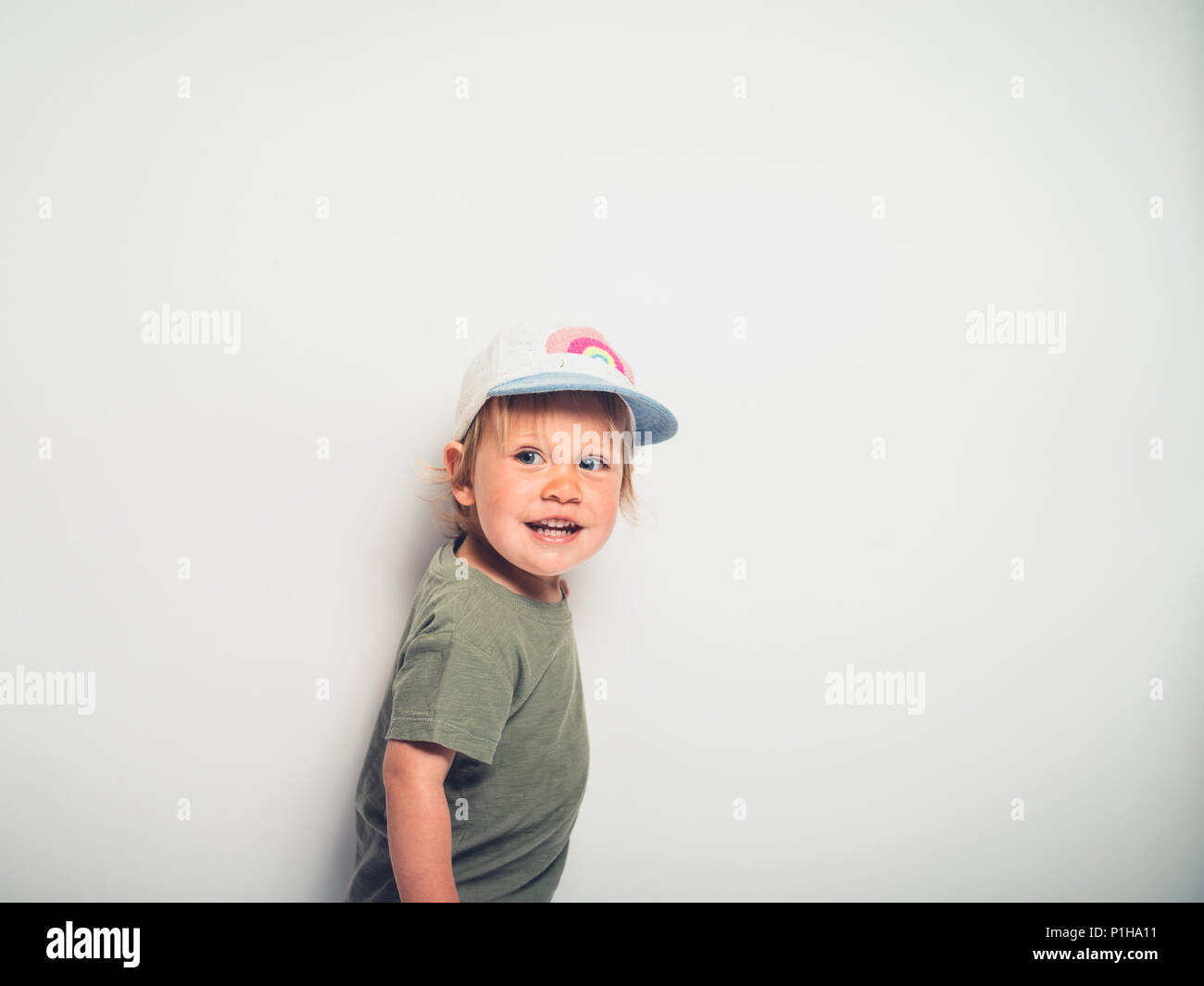 A cute little toddler boy wearing a baseball cap is striking a pose on a white background Stock Photo