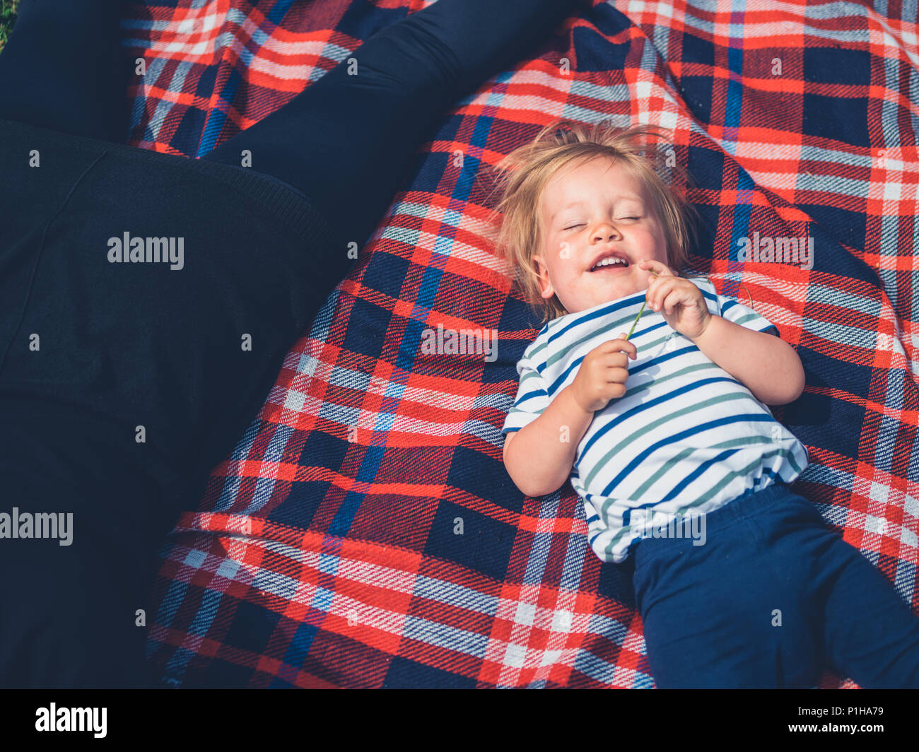 A cute little toddler boy is having a great time chilling out on a picnic blanket Stock Photo