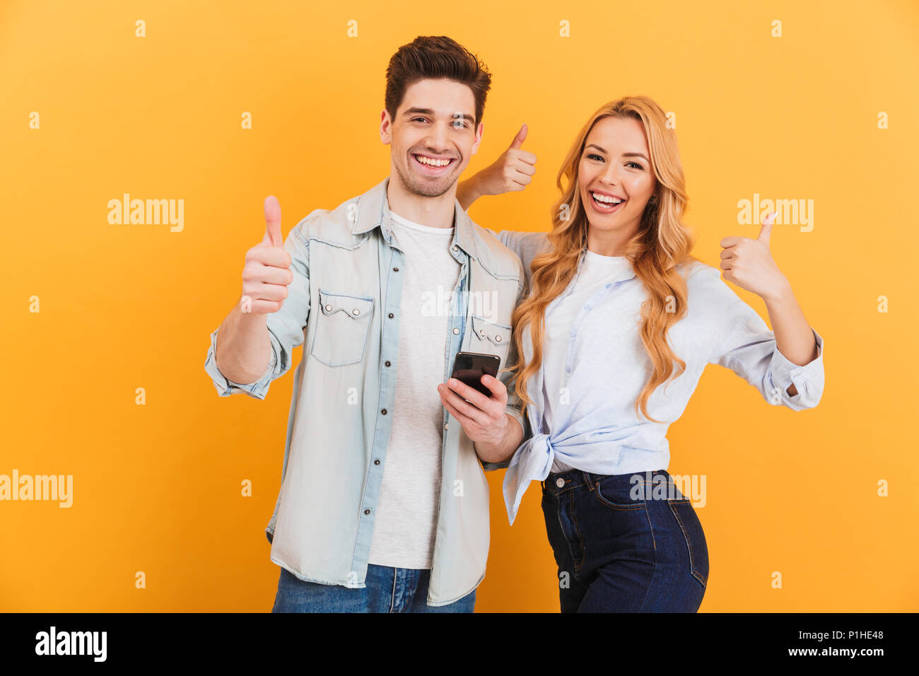 Photo of joyous couple man and woman smiling and showing thumbs up ...