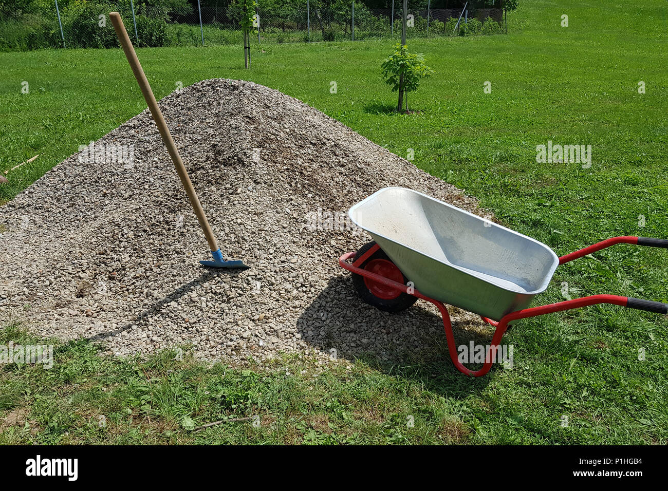Construction wheelbarrow shovel on a pile of a rock gravel in a garden. Stock Photo