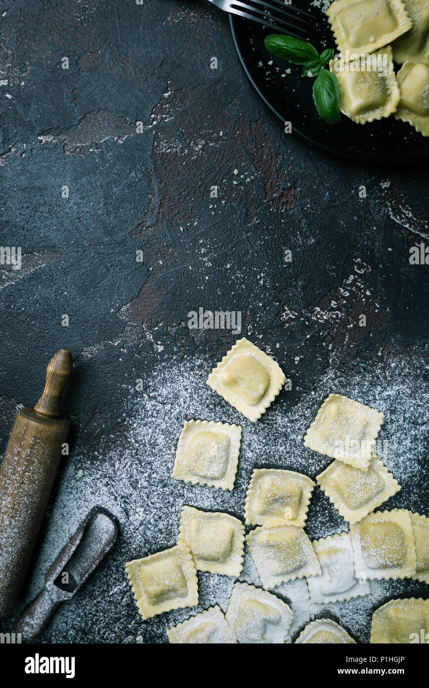 Fresh ravioli with flour on dark stone background, top view. Cooking ...